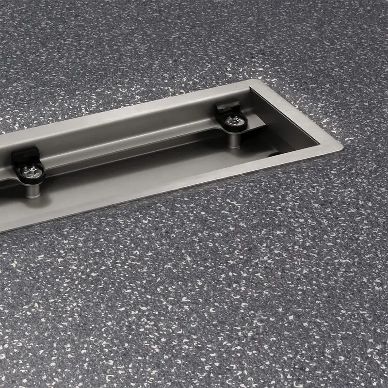 Wiper VF drain set into a speckled vinyl floor, with the clamping frame screwed down over the vinyl edge